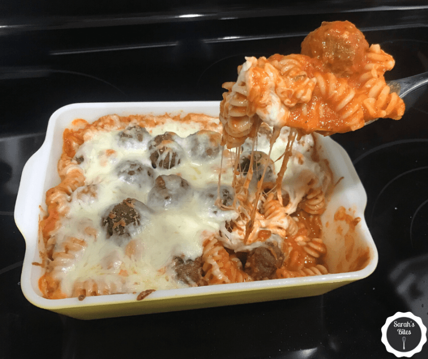 Pasta with cheese and meatballs being spooned out of the baking dish